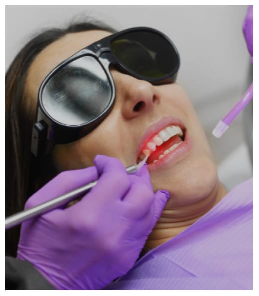Patient receiving dental examination with protective eyewear and purple gloves in dental office.