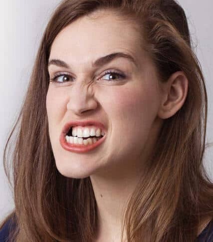 Woman smiling brightly showing white teeth against neutral background for dental practice