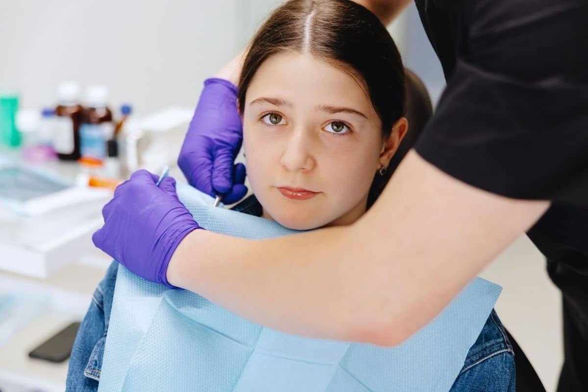 Young girl in a dental chair with a dental professional preparing her for treatment