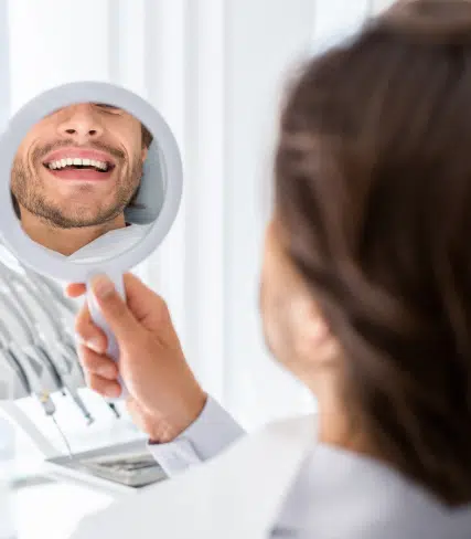 Patient with bright smile checking his new smile on mirror