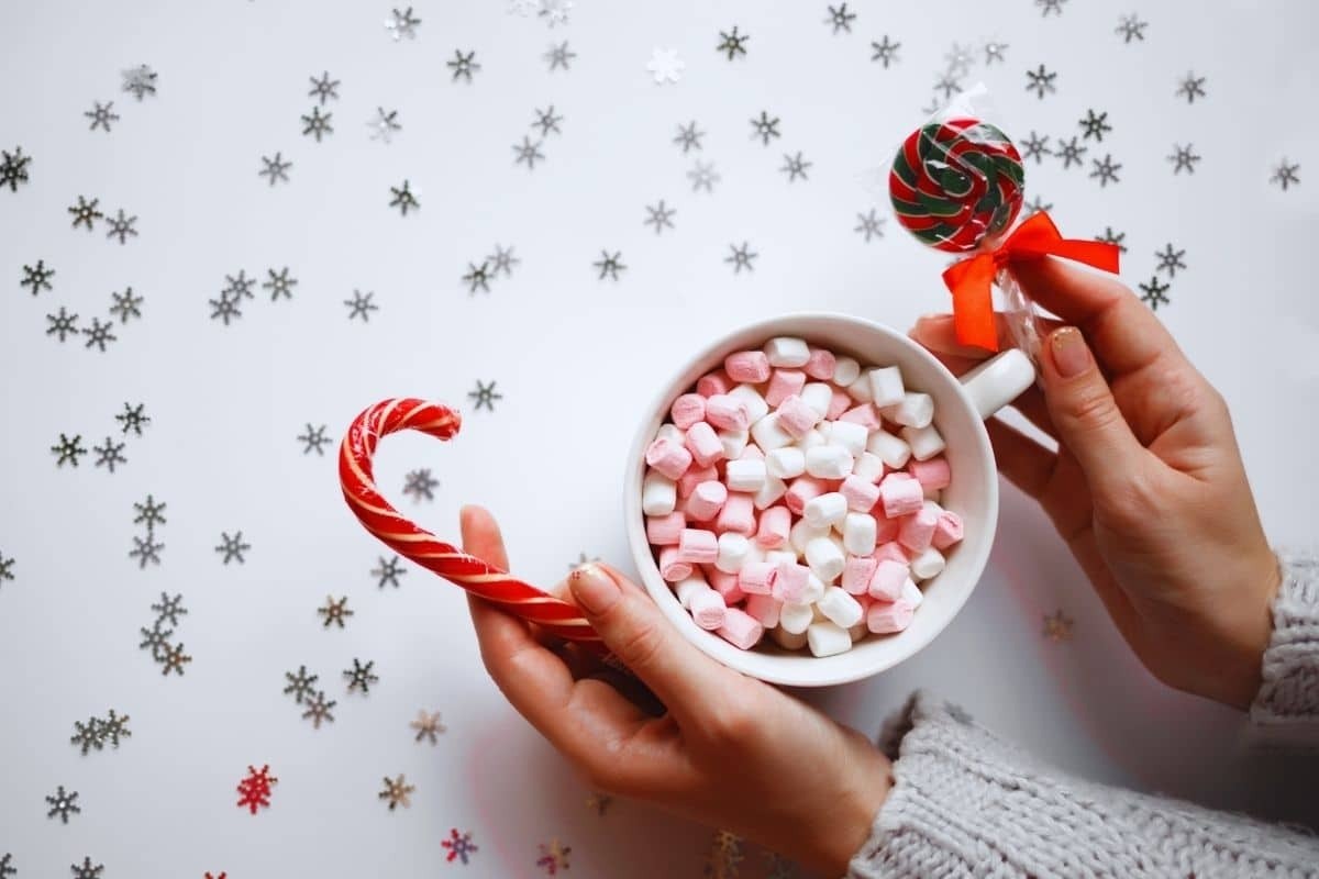 Close-up of hands holding colorful holiday Christmas candies, illustrating the impact on teeth.